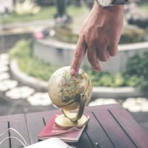 Touching a globe that is on top of a passport