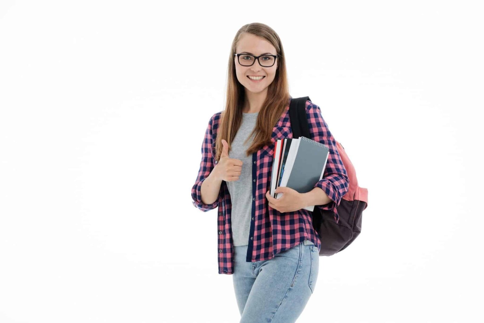 A young student holding books, carrying a backpack and holding her thumb up